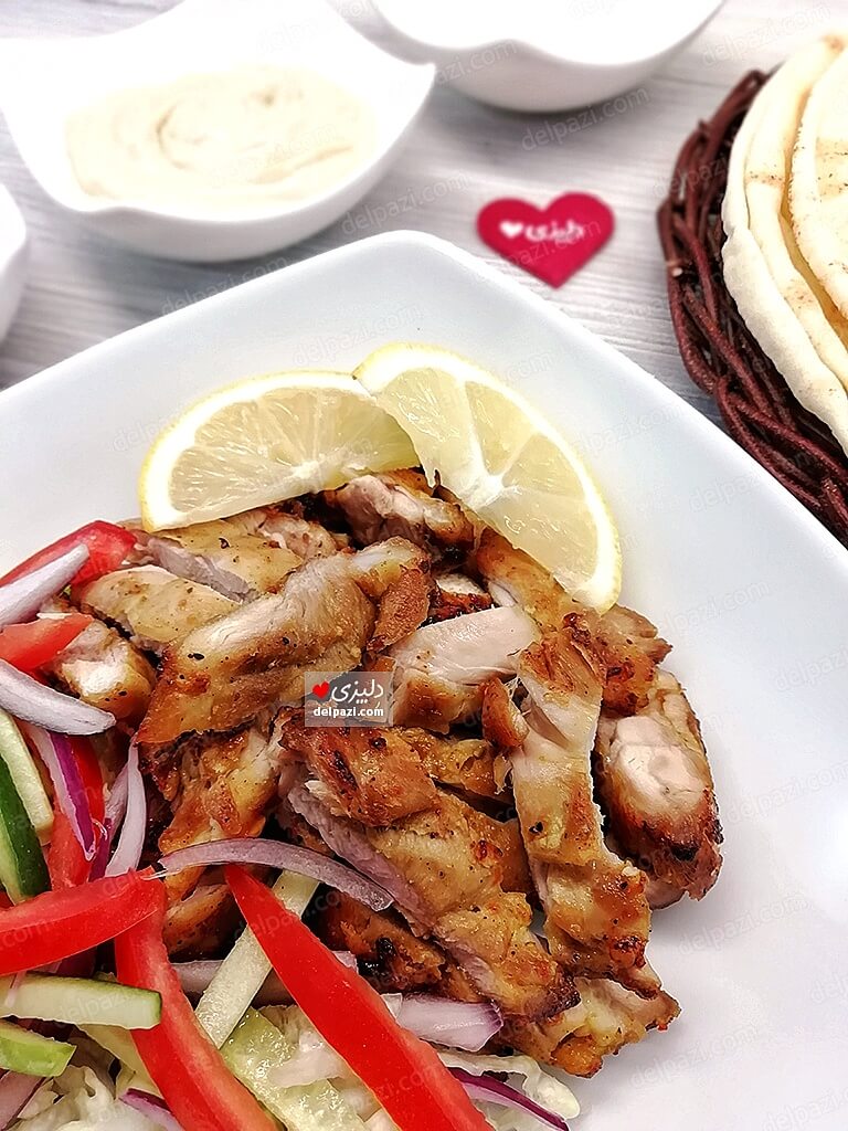 شاورما مرغ به صورت پرسی ، تهیه شده از ران مرغ به همراه دورچین، سس تاهینی و نان پیتا برای تهیه ساندویچ مرغ شاورما دلپزی